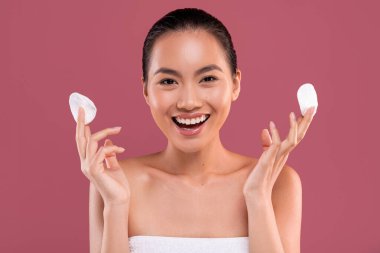 Pamuklu ped tutan Koreli olumlu bir kadın.