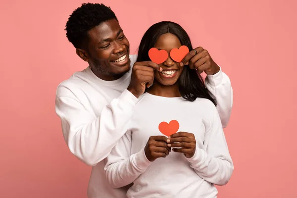 Amare ragazzo nero che copre i suoi occhi fidanzata con carte di San Valentino — Foto Stock