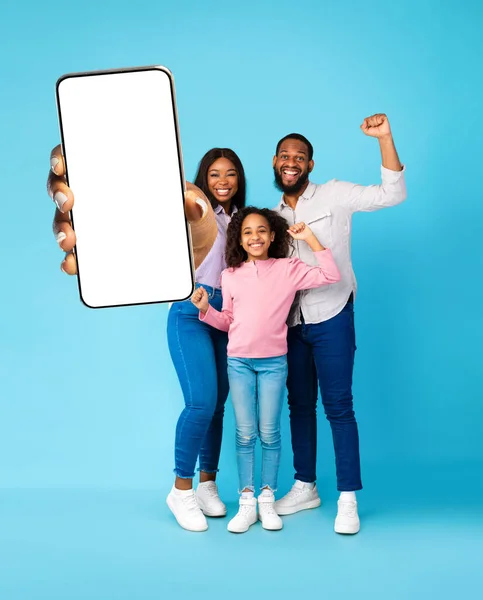 Zwarte familie toont lege smartphone scherm en schudden vuisten — Stockfoto