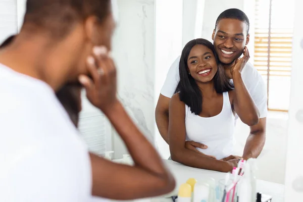 Feliz joven negro pareja mirando espejo en cuarto de baño y abrazando — Foto de Stock