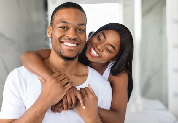 Portrait Of Happy Young Black Spouses Embracing In Bathroom Interior — стоковое фото