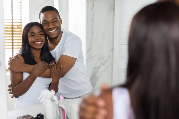 Een paar huiselijk leven. Romantische zwarte echtgenoten omhelzen in de buurt van spiegel in de badkamer — Stockfoto
