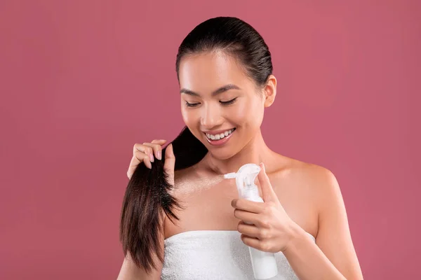 Uzun saçlı mutlu Asyalı kadın saç spreyi kullanıyor. — Stok fotoğraf