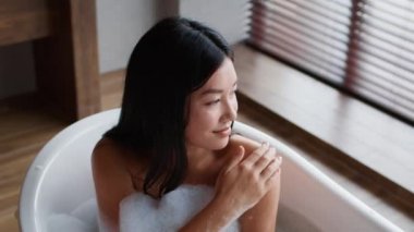 Japanese Woman Applying Scrub Caring For Body Bathing In Bathroom