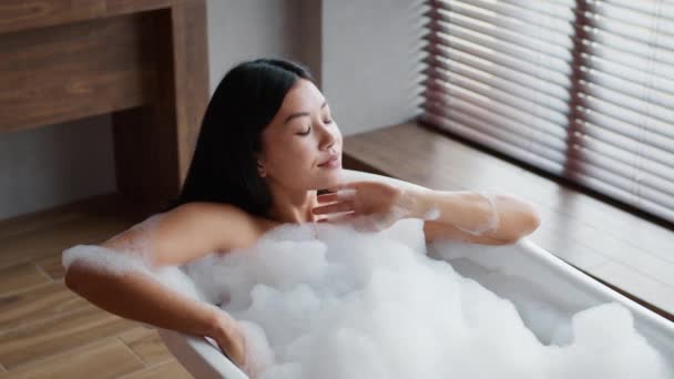 Femme coréenne prenant bain relaxant avec de la mousse dans la salle de bain intérieure — Video