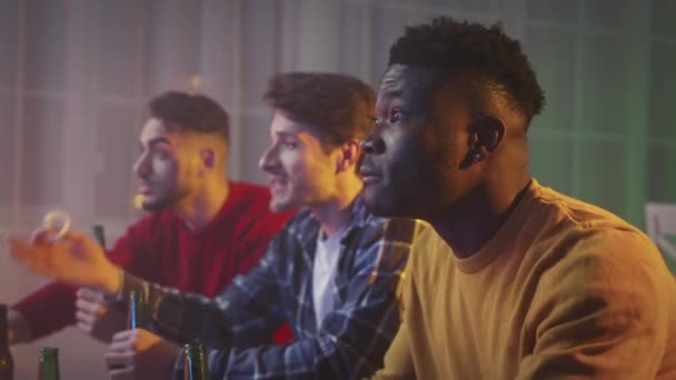 Young emotional african american guy cheering his favorite soccer team, watching sport match on tv with diverse friends — Vídeo de stock