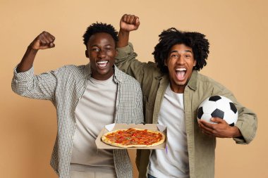 İki heyecanlı Siyahi Futbol Hayranı Futbol ve Pizza Tutuyor