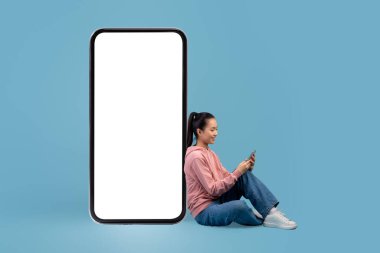 Cep telefonunun başında oturan mutlu Japon kadın mobil uygulama kullanıyor.