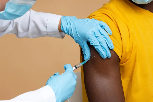 Vaccinationsprocess. Oigenkännlig läkare att göra injektion till svart man patient — Stockfoto