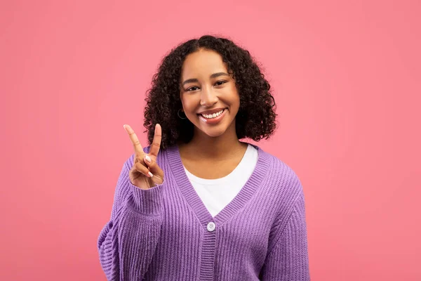 Positive mood. Portrait of joyful young black woman showing victory gesture on pink studio background — Foto de Stock