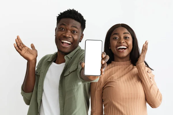Emocional pareja afroamericana mostrando teléfono inteligente con pantalla vacía, maqueta — Foto de Stock