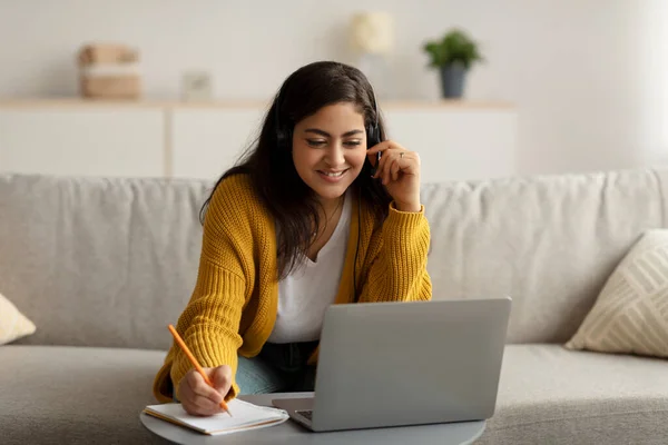 Online onderwijs concept. gelukkig midden oosten vrouw in headset studeren met laptop thuis en het maken van notities — Stockfoto