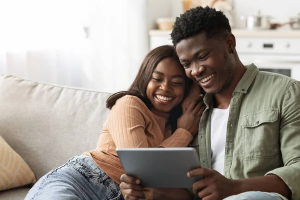 Happy black lovers using digital tablet together, home interior —  Fotos de Stock