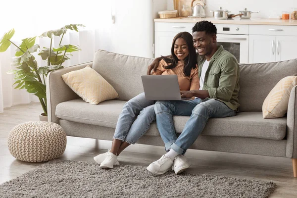 Loving black couple using laptop together, home interior — Stockfoto