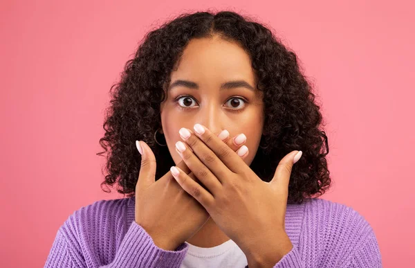 Oops. Amazed young African American woman covering mouth with hands, shocked by news or offer on pink background — Stock Fotó