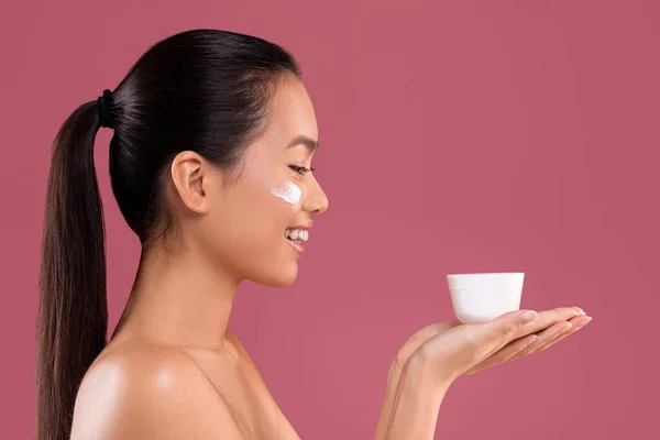 Happy korean woman showing her favourite beauty product, side view — 스톡 사진