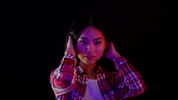 Beautiful Asian Woman In Neon Lights Touching Hair And Looking At Camera — Wideo stockowe