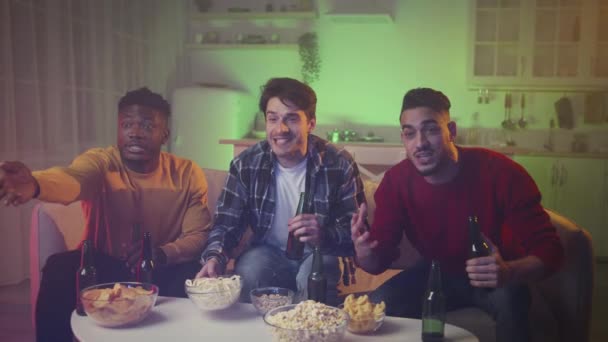 Three young diverse men friends watching football match on tv at home, emotionally supporting favorite soccer team — Stock video