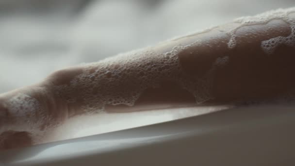 Close up of young african american woman taking relaxing foamy bath at home, lying in bathtub and dancing, tracking shot — Stok video