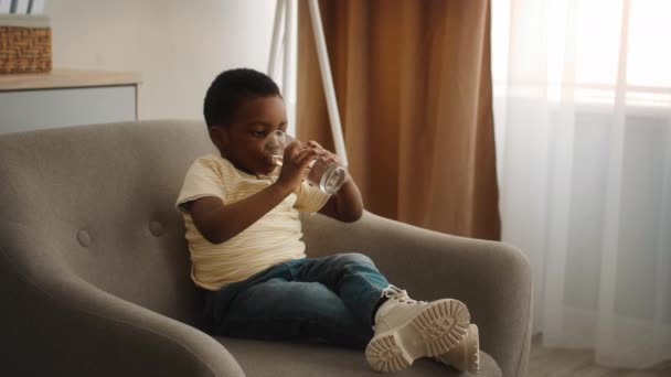 Cute Little Black Boy Drinking Water From Glass While Relaxing At Home — Video Stock