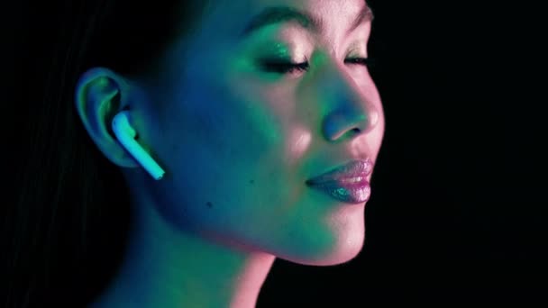 Young Asian Woman Listening Music In Wireless Airpods Earphones In Neon Light — Stok video