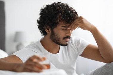 Depresyondaki Hintli adam içki içiyor, yatak odası içi, yakın plan.