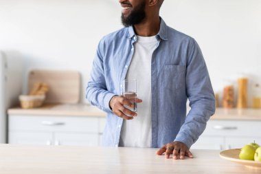 İyi ki sakallı Afro-Amerikan genç adam günaydın ve mutfağın içinde bir bardak temiz suyun tadını çıkarıyor.