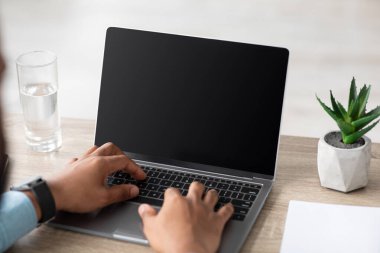 Genç Afro-Amerikalı adam, iç işlerinde boş ekranla bilgisayarda yazı yazıyor. Kapatın.