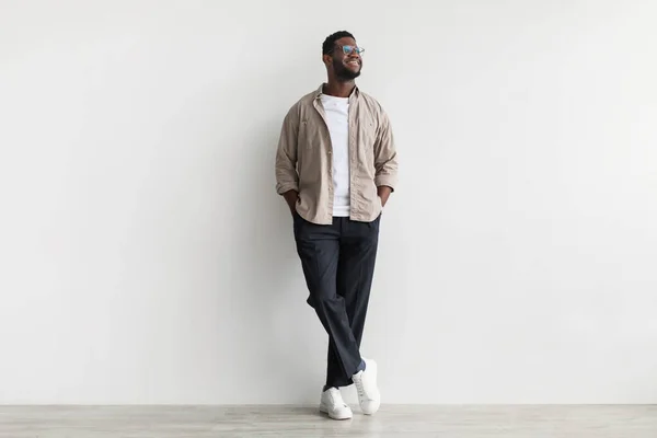 Full length of handsome young African American man wearing casual clothes, looking aside, posing against white wall — 图库照片