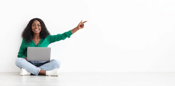Smiling black woman with laptop showing empty space — ストック写真