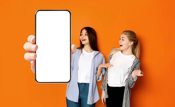 Excited women showing white empty smartphone screen close to camera — 스톡 사진