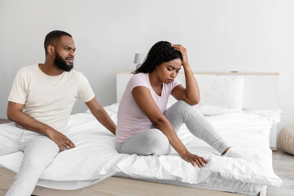 Young black couple having relationships crisis, sitting separated on bed — Stock Photo © Milkos #379388286