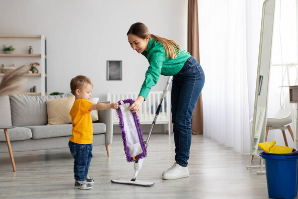 Happy family cleaning the room. Mother and toddler son doing the cleaning at home, kid boy helping mom washing floor
