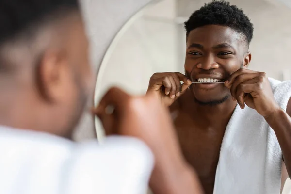 Alegre hombre negro usando hilo dental en el baño — Foto de Stock