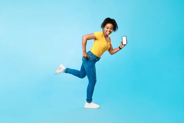 거대 한 온라인 판매입니다. 행복 한 젊은 흑인 여성의 전체 길이 와 빈 스마트폰 이 파란 스튜디오 배경에서 실행되는 — 스톡 사진