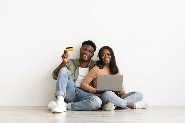 Emocional pareja afroamericana usando portátil y tarjeta de crédito —  Fotos de Stock