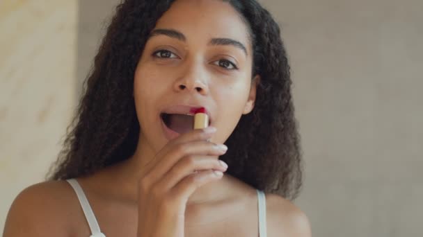 젊고 아름다운 아프리카계 미국 여성 입술에 빨간 립스틱을 바르고, 데이트 준비를 집에서 하고, 거울 포 브 초상화 — 비디오