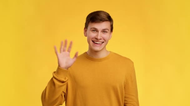 Веселий чоловік махає рукою Гештег Привіт над жовтим фоном студії — стокове відео