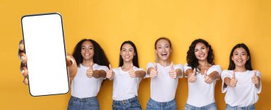 Mutlu kadınlar boş akıllı telefon ekranı ve başparmak kaldırıyor