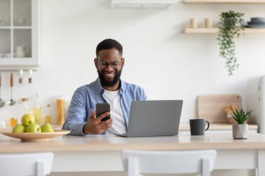 Gülümseyen, sakallı iş adamı Afro-Amerikan vatandaşı akıllı telefondan posta kontrolü yapıyor.