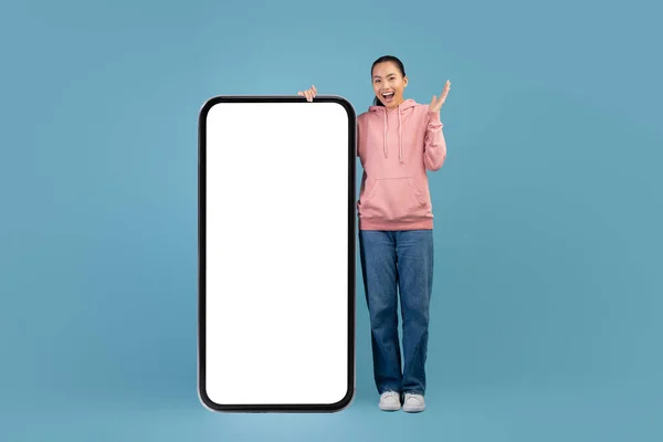 Excited korean millennial woman posing with big smartphone — 图库照片