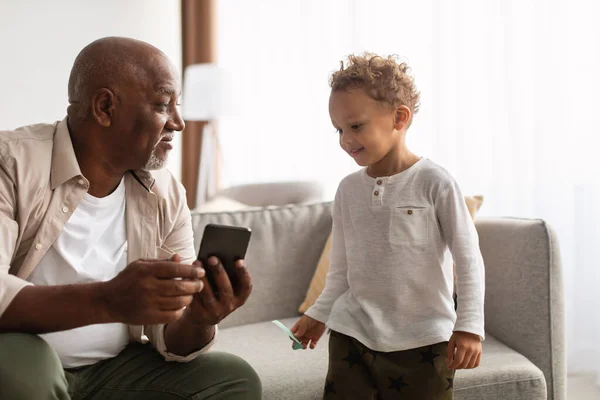 African American Grandpa And Grandson Using Phone Sitting At Home — Fotografia de Stock