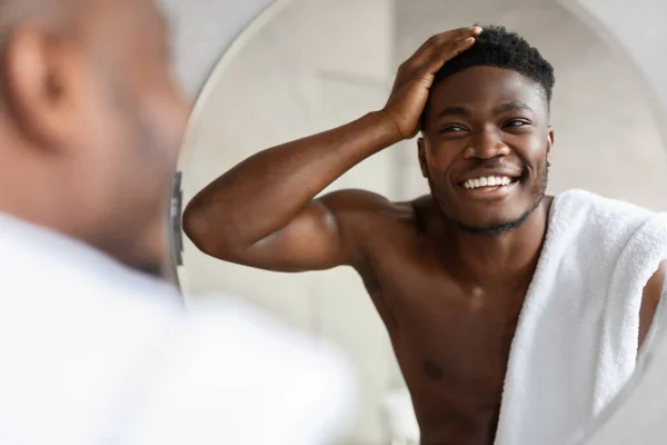 Feliz africano chico tocando pelo corto mirando espejo interior — Foto de Stock