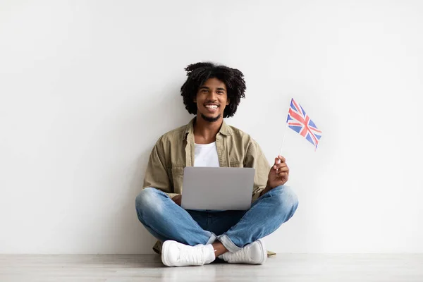 Smiling African American Guy Sitting On Floor With Laptop And Britain Flag — 스톡 사진