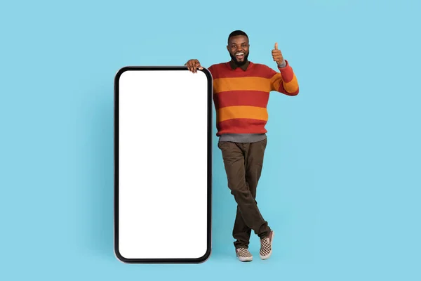 Nice Offer. Happy Black Man Leaning On Big Smartphone With Blank Screen — 图库照片