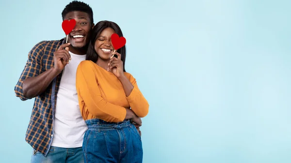 Young Black Couple Covering Eyes With Red Paper Hearts, Panorama — Stockfoto