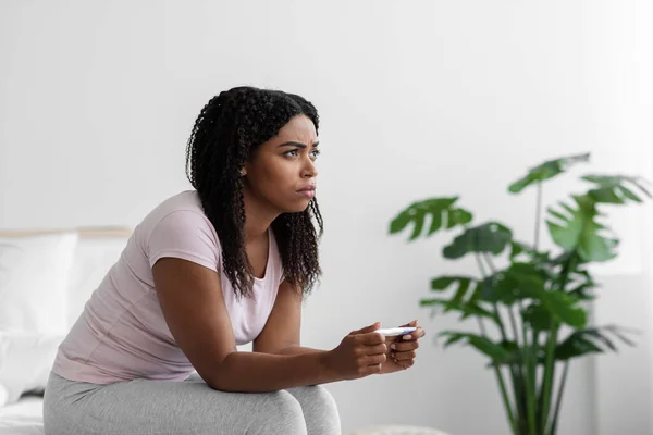 Frustrated sad young black woman sitting on bed and looking at negative pregnancy test have female health problems — Stock Photo, Image