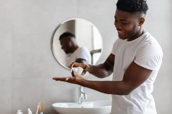 Africano hombre apretando líquido jabón de botella en cuarto de baño — Foto de Stock