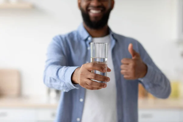 Smiling young black man with beard enjoy good morning, show glass of clean water and thumb up — Foto Stock