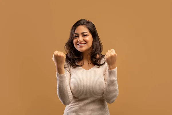 Win concept. Overjoyed arab woman cheering and celebrating victory, shaking clenched fists on beige studio background — ストック写真